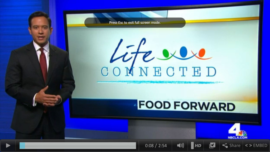Newscaster standing in front of screen with segment name